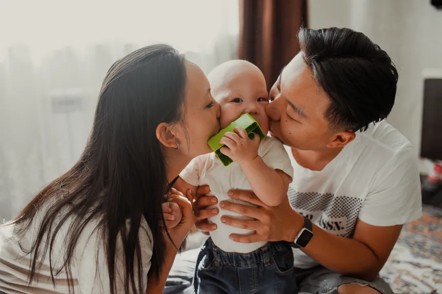 Parents kissing baby
